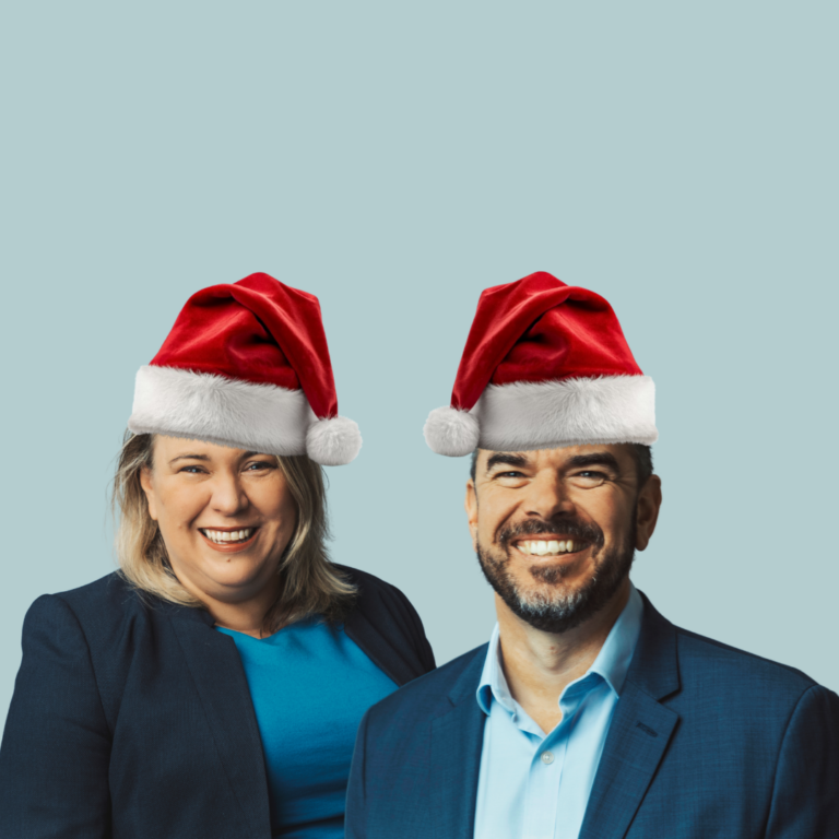 Man and woman in business attire wearing red and white Santa hats on a light blue background